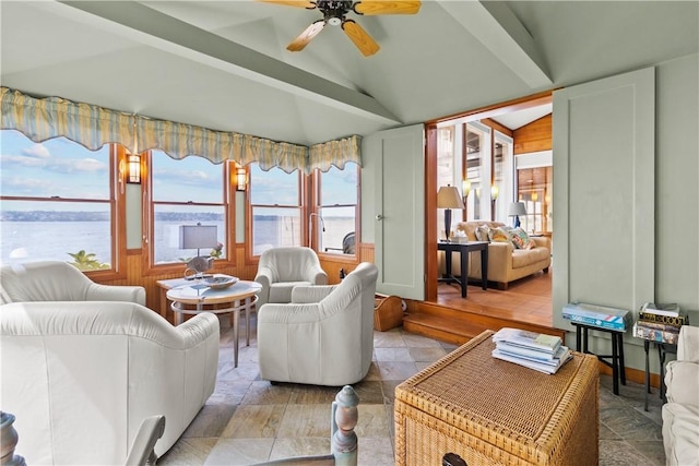 living room with a wealth of natural light, a water view, and lofted ceiling