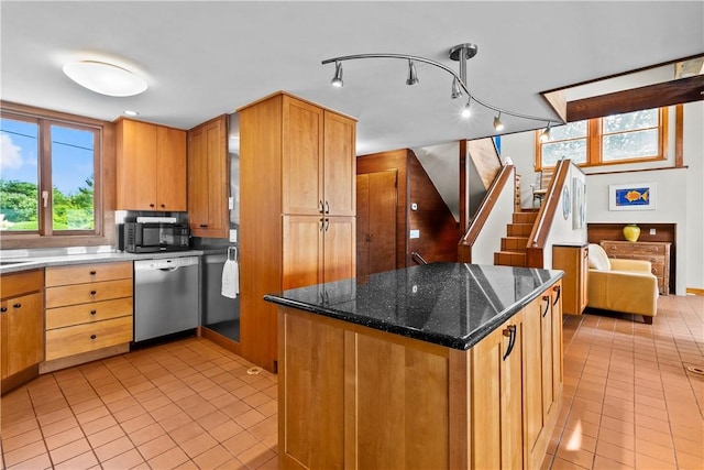 kitchen with dark stone countertops, light tile patterned floors, black microwave, a center island, and dishwasher