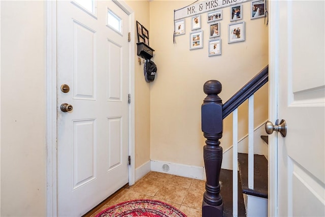 entrance foyer featuring light tile patterned floors, baseboards, and stairs