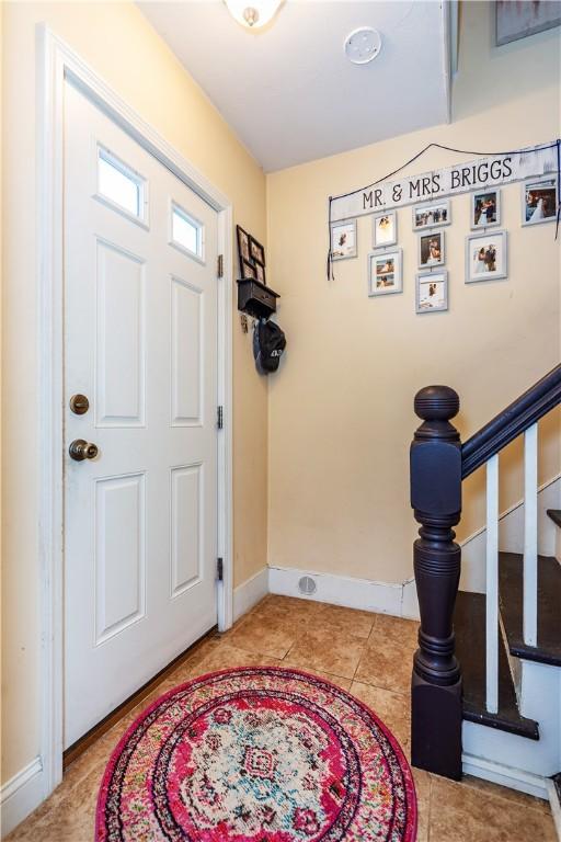 foyer entrance featuring baseboards, tile patterned flooring, and stairway