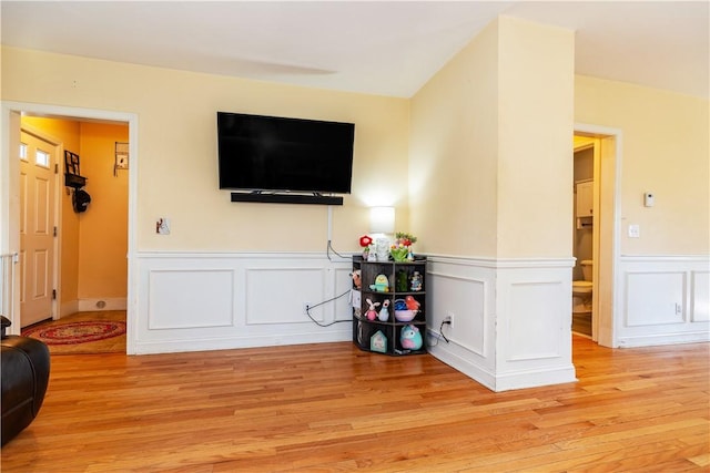 living area featuring light wood-type flooring and wainscoting