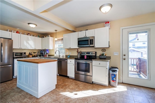 kitchen with light tile patterned flooring, white cabinets, stainless steel appliances, butcher block counters, and decorative light fixtures