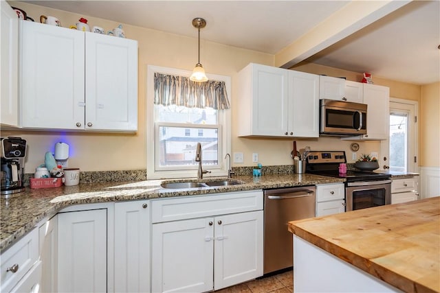 kitchen with a sink, white cabinetry, appliances with stainless steel finishes, butcher block counters, and plenty of natural light