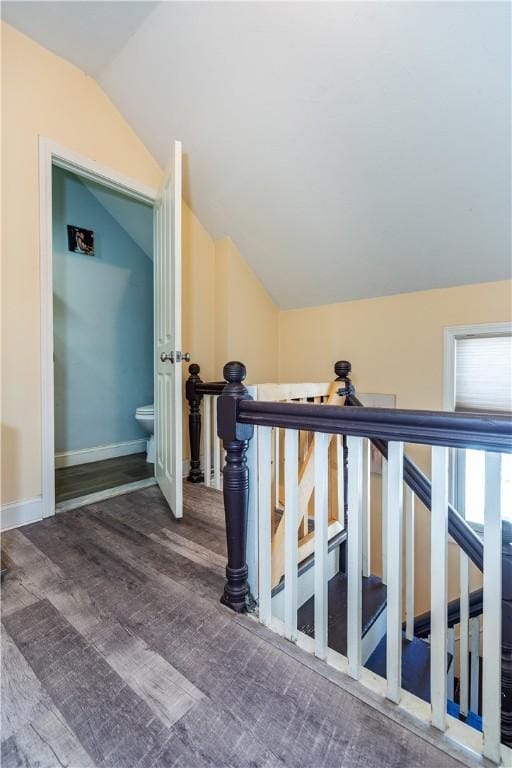 staircase featuring baseboards, lofted ceiling, and wood finished floors