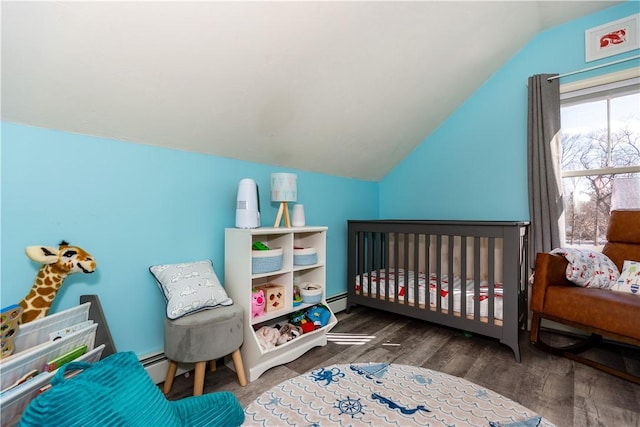 bedroom featuring a crib, lofted ceiling, a baseboard heating unit, and wood finished floors