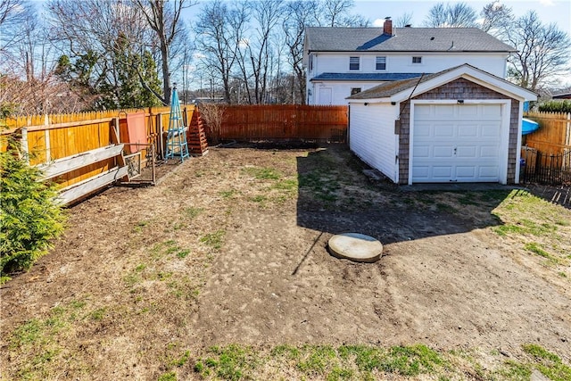 view of yard featuring a fenced backyard, an outbuilding, and a garage
