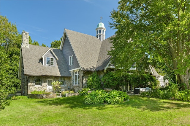 exterior space featuring stone siding, a chimney, a shingled roof, and a lawn