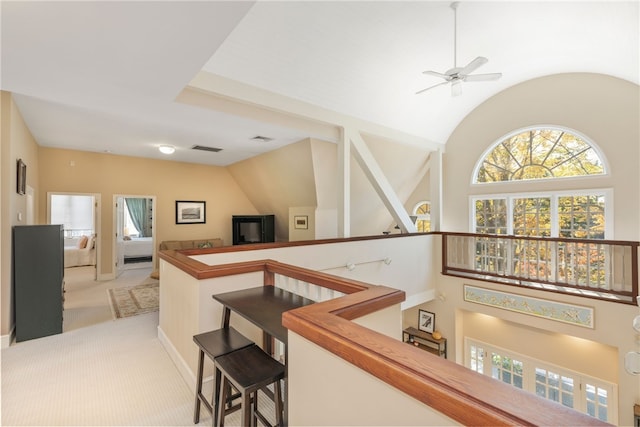 hall featuring light carpet, visible vents, an upstairs landing, and lofted ceiling