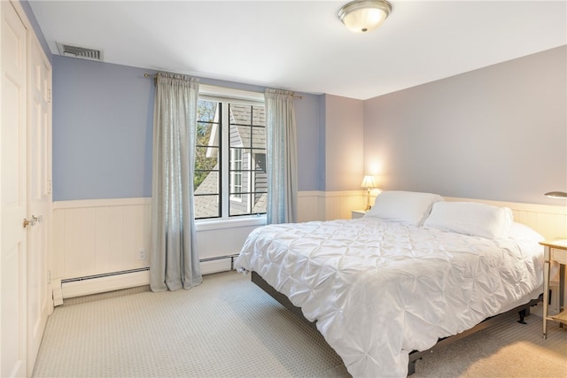 bedroom with a wainscoted wall, a baseboard radiator, visible vents, and carpet