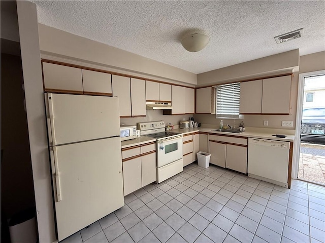 kitchen with light countertops, a sink, under cabinet range hood, white appliances, and visible vents