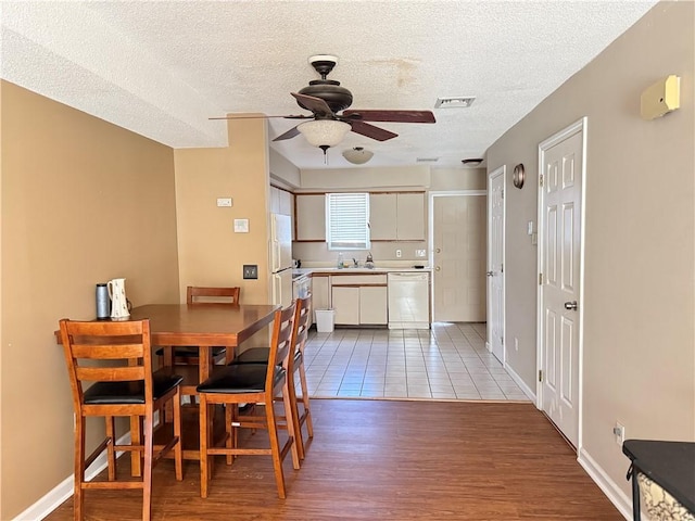 dining room featuring visible vents, wood finished floors, ceiling fan, and a textured ceiling