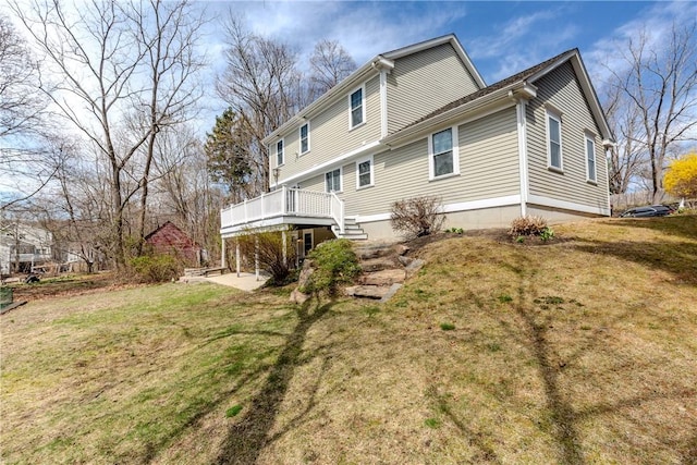 back of property with a yard, a deck, and stairway