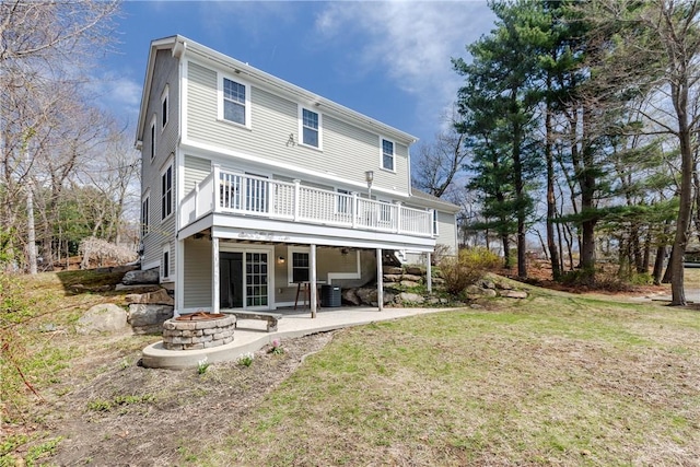 rear view of property with a lawn, a deck, a fire pit, and a patio area