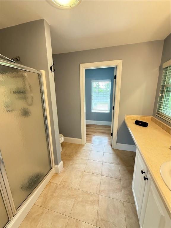 full bath featuring tile patterned floors, baseboards, a shower stall, and toilet