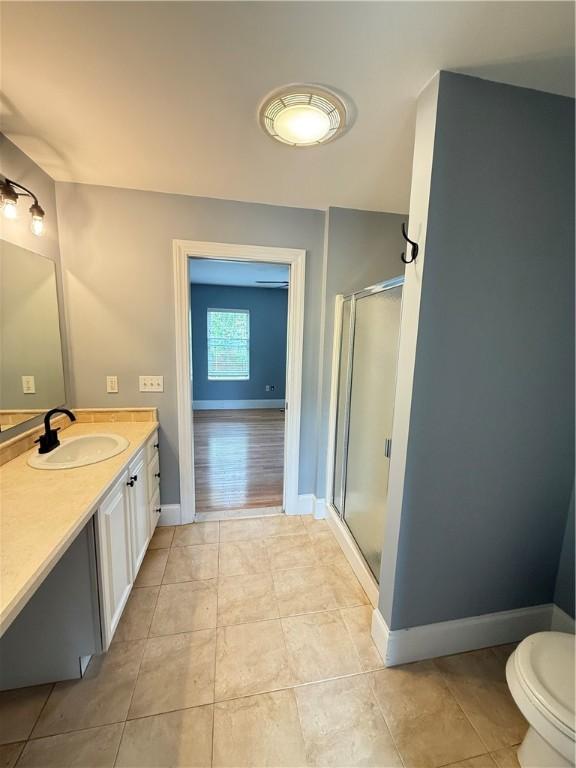full bathroom with a shower stall, baseboards, tile patterned floors, vanity, and toilet