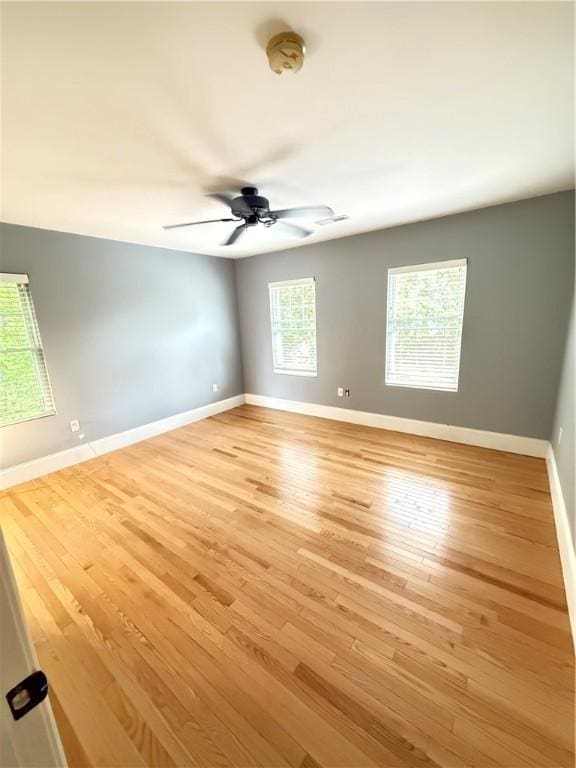 spare room with baseboards, a ceiling fan, and light wood finished floors