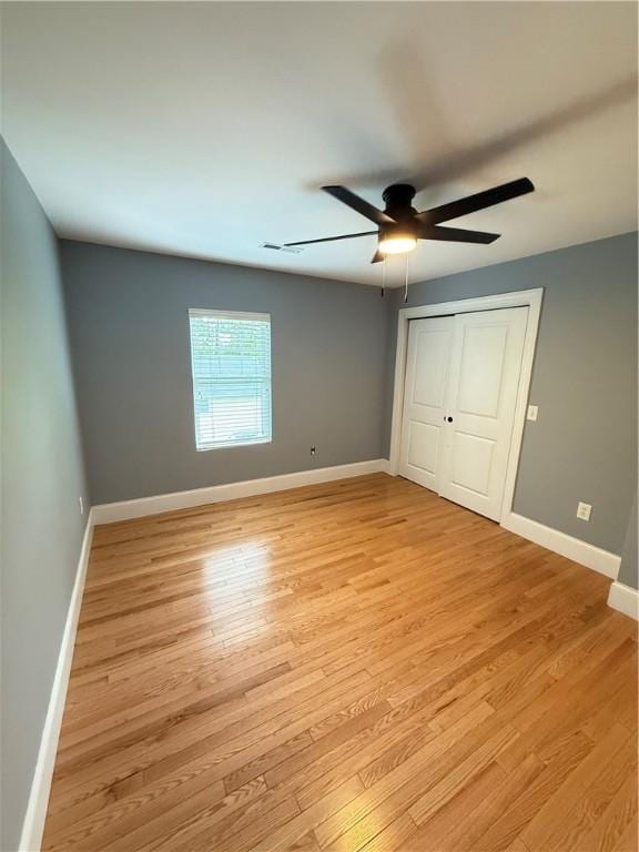 unfurnished bedroom featuring baseboards, ceiling fan, light wood finished floors, and a closet