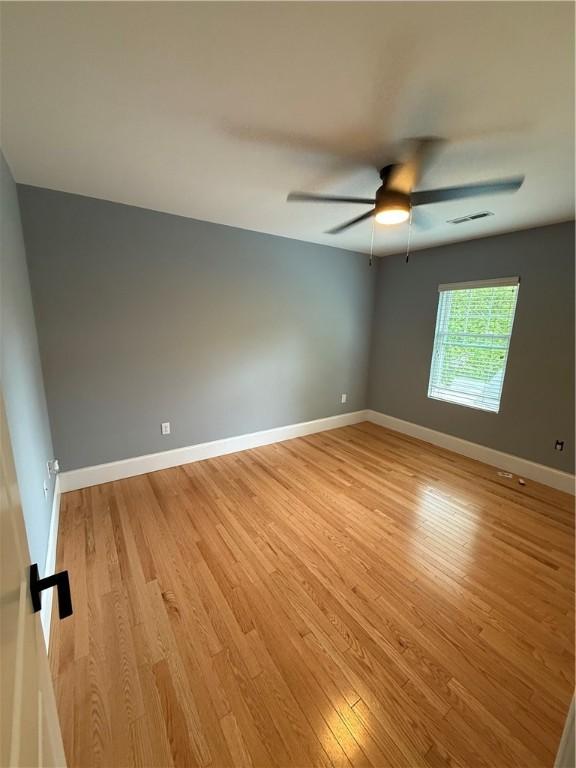 unfurnished room with a ceiling fan, baseboards, visible vents, and light wood-style floors