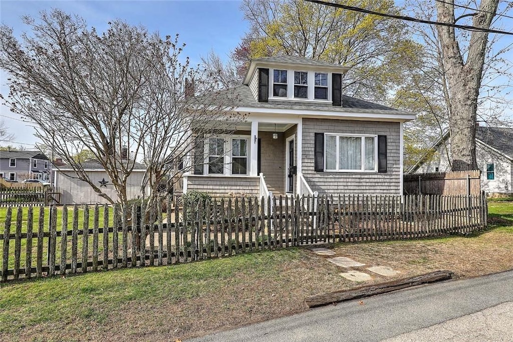 view of front of house featuring roof with shingles, a porch, and a fenced front yard