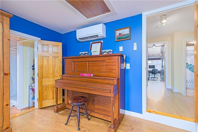 office space with baseboards, wood finished floors, and a wall mounted air conditioner