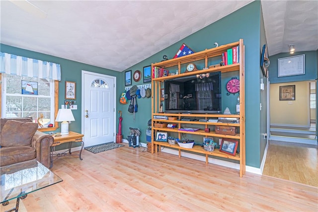 living room featuring baseboards, vaulted ceiling, and wood finished floors