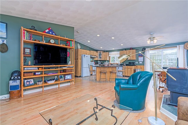 living area with plenty of natural light, lofted ceiling, light wood-style flooring, and a ceiling fan