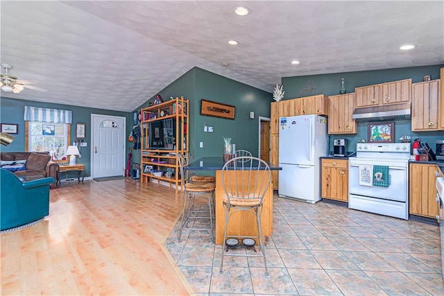 kitchen featuring vaulted ceiling, white appliances, under cabinet range hood, dark countertops, and a ceiling fan