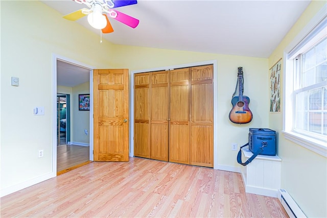 bedroom featuring a baseboard radiator, vaulted ceiling, a closet, and light wood-type flooring