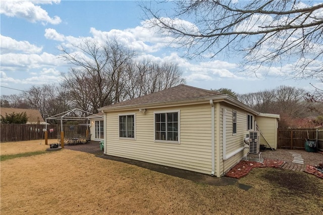 exterior space featuring a shingled roof, a fenced backyard, a gazebo, and a yard