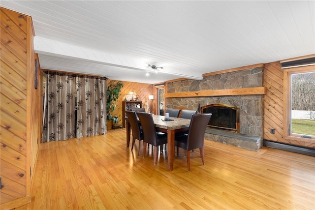 135 Eagleville Rd, Tiverton, RI 02878 - dining room featuring wood finished floors, wooden walls, wood ceiling, a baseboard heating unit, and a stone fireplace