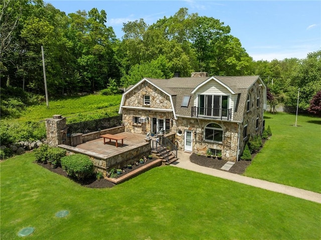 135 Eagleville Rd, Tiverton, RI 02878 - back of property featuring stone siding, a balcony, a yard, a gambrel roof, and a wooden deck