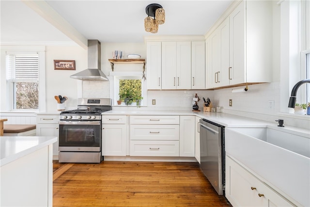 4588 Main Rd, Tiverton, RI 02878 - kitchen featuring light countertops, wall chimney exhaust hood, appliances with stainless steel finishes, a sink, and light wood-type flooring