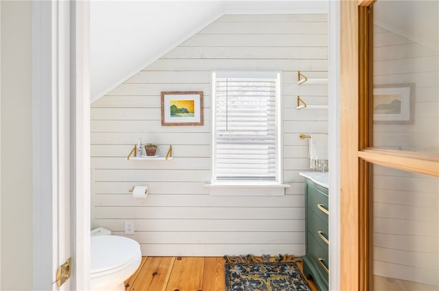 4588 Main Rd, Tiverton, RI 02878 - half bath with vanity, vaulted ceiling, toilet, wooden walls, and wood finished floors