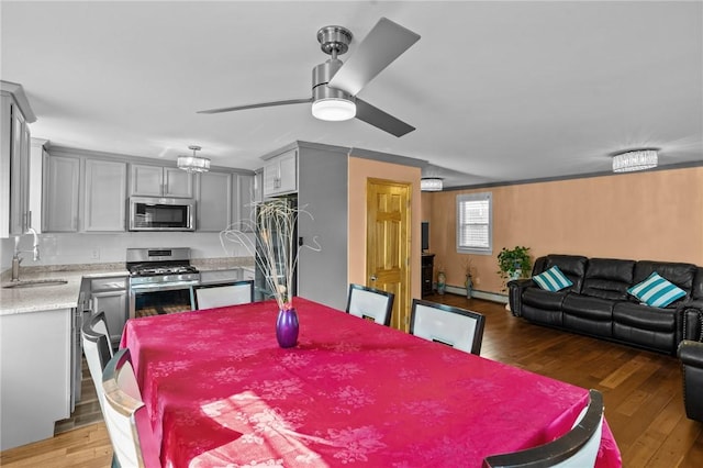 dining room with light wood-style floors, a baseboard heating unit, and a ceiling fan
