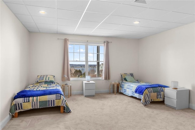 carpeted bedroom featuring baseboards and a drop ceiling