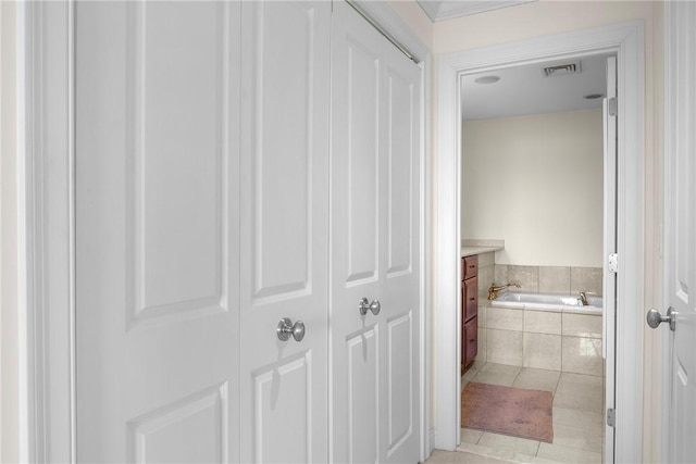bathroom with tile patterned flooring, vanity, a bath, and visible vents