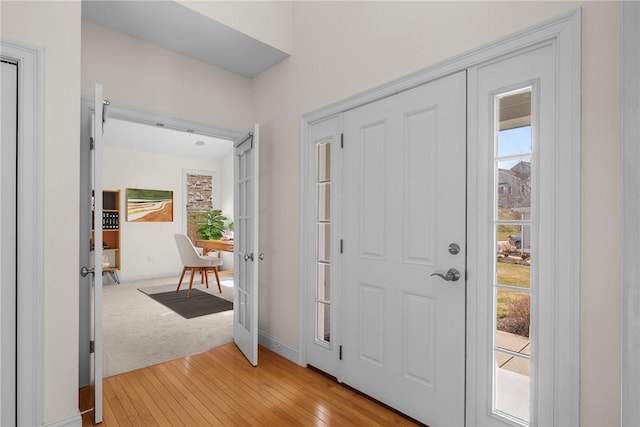 foyer with baseboards, light wood-type flooring, and light carpet