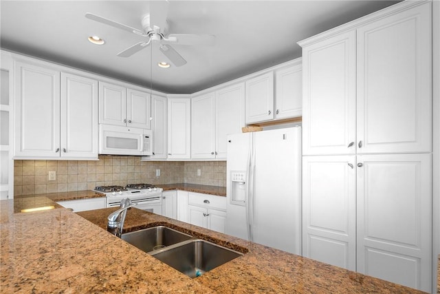 kitchen with white appliances, white cabinetry, tasteful backsplash, and a sink