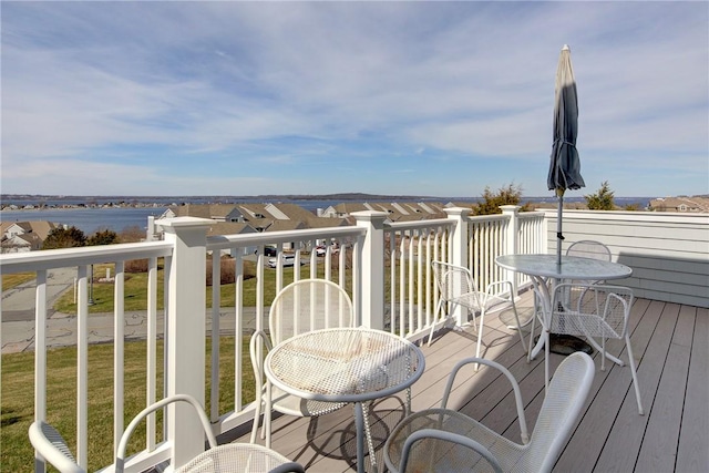 deck with outdoor dining area and a water view