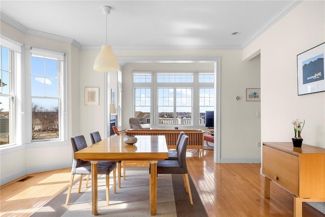 dining space featuring baseboards, visible vents, light wood-style flooring, and crown molding