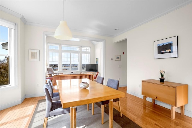 dining area with a wealth of natural light, light wood-type flooring, baseboards, and ornamental molding