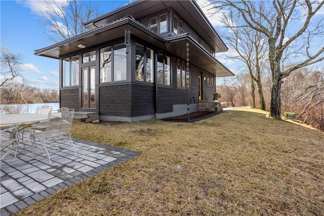 view of property exterior with a yard, a sunroom, a patio area, and french doors