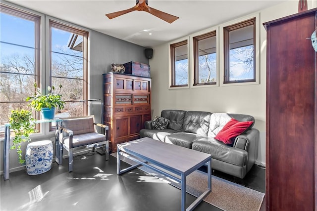 living area with ceiling fan, healthy amount of natural light, and finished concrete flooring