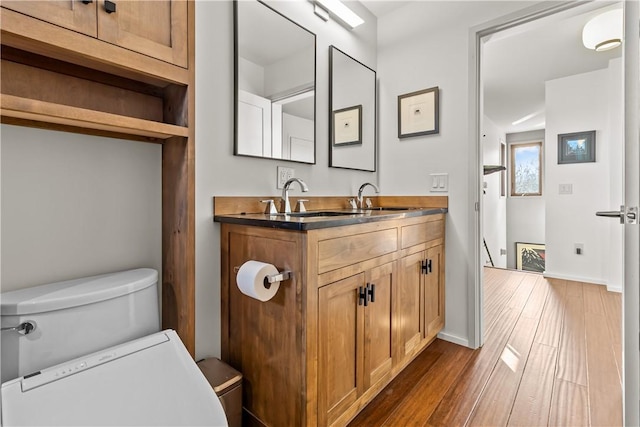 bathroom with wood finished floors, vanity, baseboards, and toilet