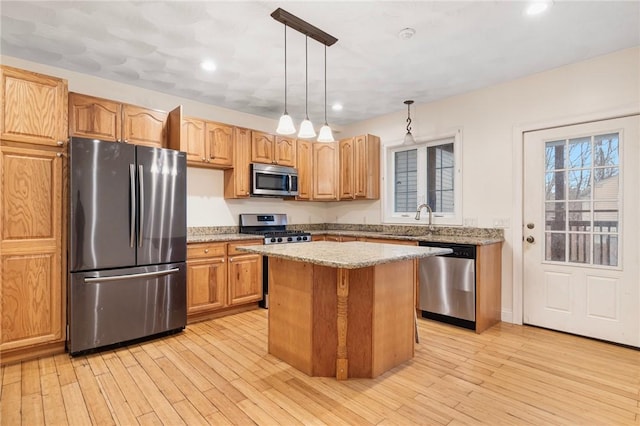 982 Plainfield St Unit 4, Johnston, RI 02919 - kitchen featuring appliances with stainless steel finishes, light stone counters, a sink, a center island, and light wood finished floors