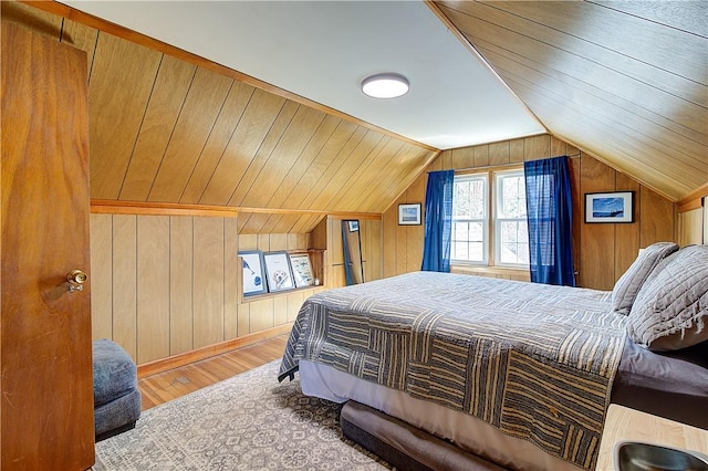 bedroom with wood finished floors, wooden walls, and vaulted ceiling