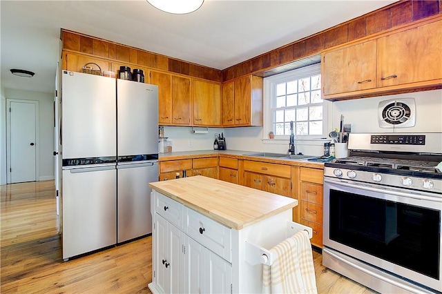 kitchen featuring a center island, white cabinets, stainless steel appliances, light wood finished floors, and a sink