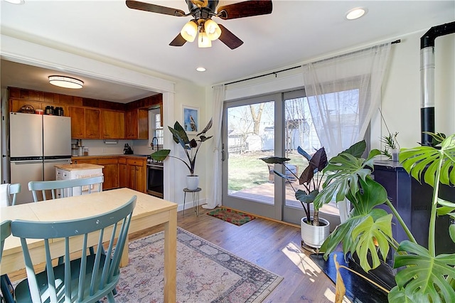 interior space featuring range with electric stovetop, ceiling fan, freestanding refrigerator, brown cabinetry, and light wood-style flooring