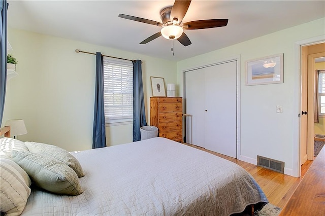 bedroom with visible vents, a closet, baseboards, ceiling fan, and light wood finished floors