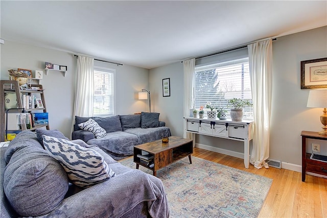 living room featuring light wood-style flooring, baseboards, and visible vents